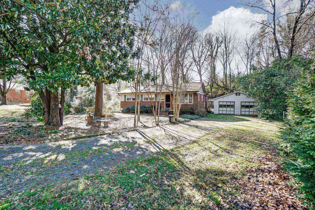 The exterior of the house, garage, and yard framed by large trees and a welcoming pathway, evoking a sense of arrival and togetherness in a classic neighborhood setting.