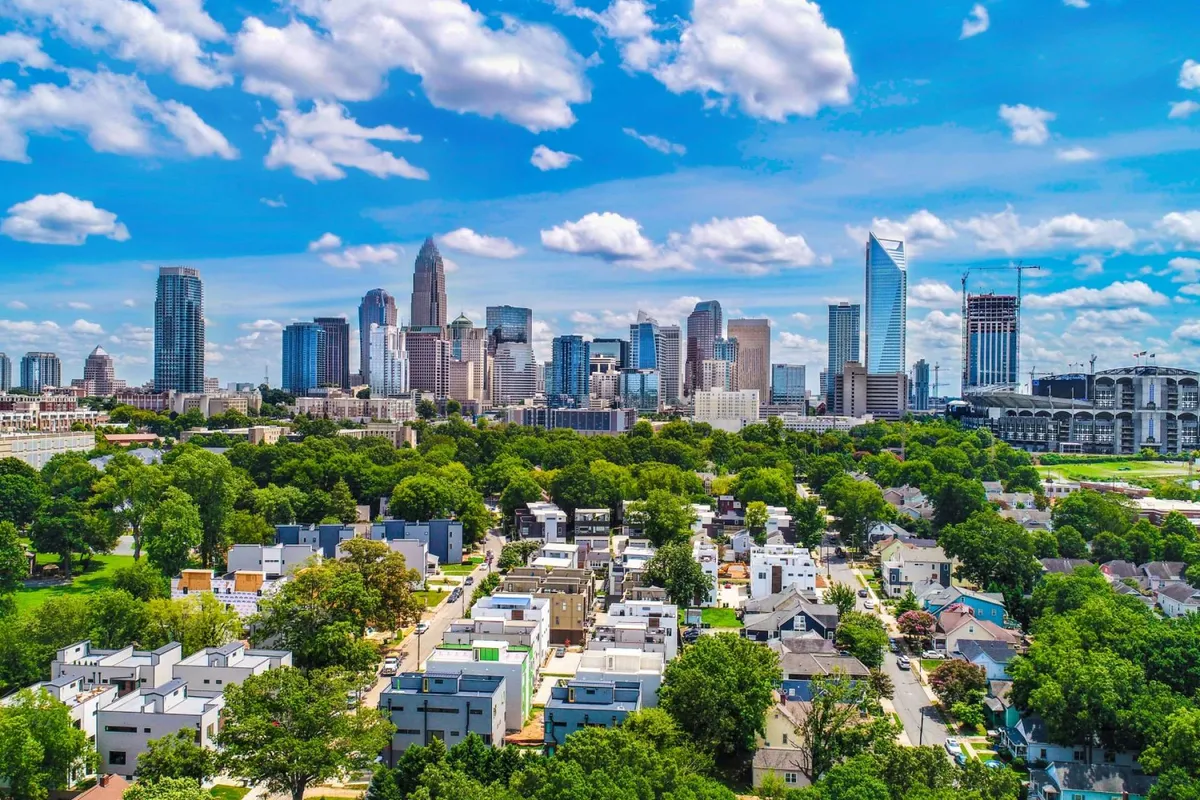 This image provides a broad view of the city skyline with green parks and residential buildings visible in the foreground. The scene conveys both the urban environment and nearby natural spaces, suggesting a vibrant, accessible community just minutes from home.