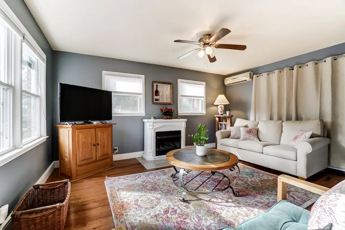 The image shows a warm, inviting living room with a plush sofa facing a cozy fireplace and a large television. The coffee table is neatly arranged, suggesting a perfect spot for gathering, relaxing, or sharing stories. The room exudes a cozy, welcoming ambiance ideal for family time or unwinding after exploring Charlotte.
